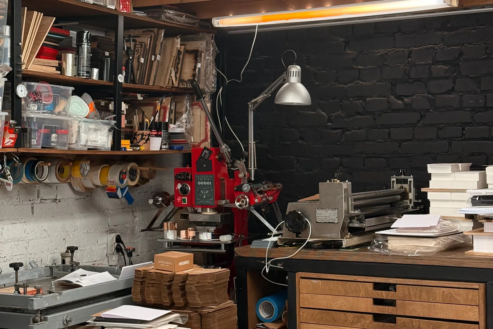 Operator working with industrial printing equipment in a compact production workshop